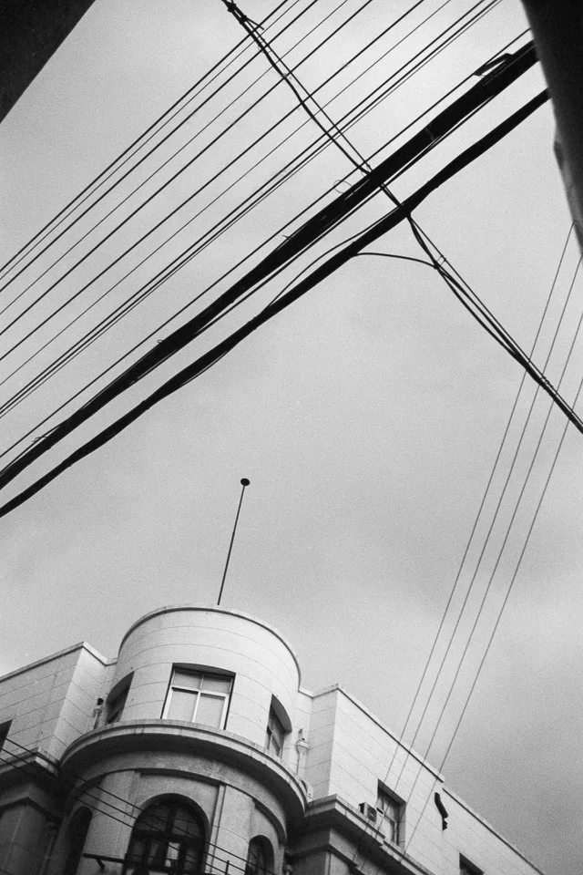 Overhead wires crossing the sky above a building