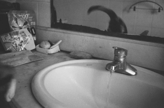 A bathroom sink and mirror in black and white