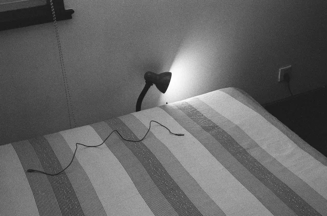 A bedside lamp casting light across a bed