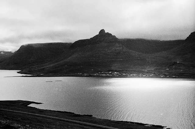A broad coastal bay beneath low clouds and a rugged flat-topped hill