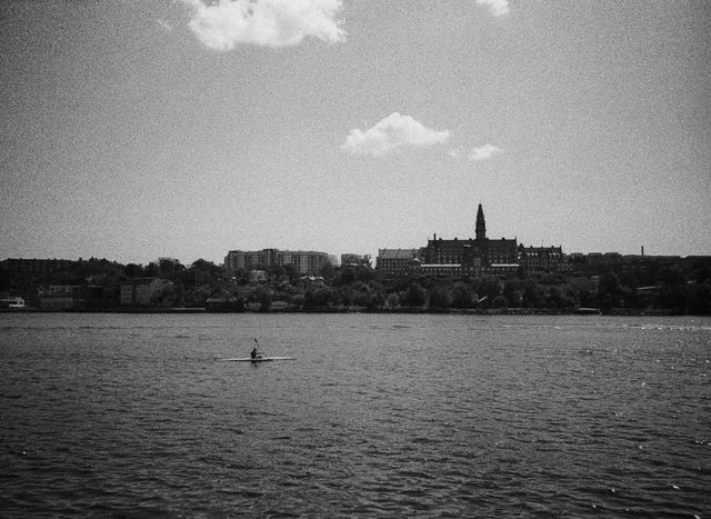 A small craft on open water below a distant city skyline