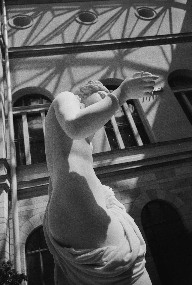 A white classical torso sculpture with a raised arm inside an ornate hall