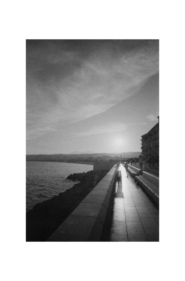 The low sun reflecting along a waterfront promenade beside calm water