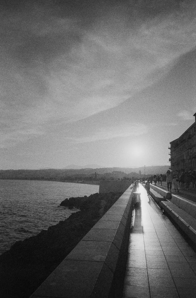 The low sun reflecting along a waterfront promenade beside calm water