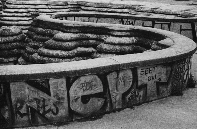 Curving graffiti-covered walls enclosing layered stone forms