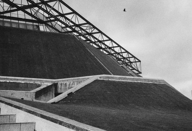 Angular concrete terraces beneath an exposed steel roof frame