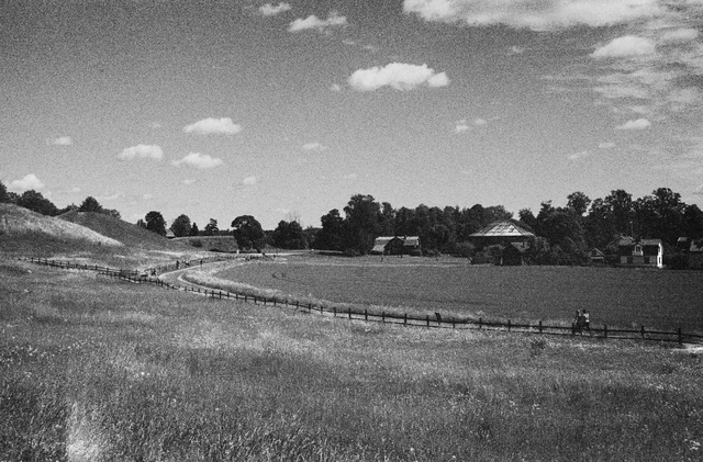 A winding path through open grassland beneath scattered clouds