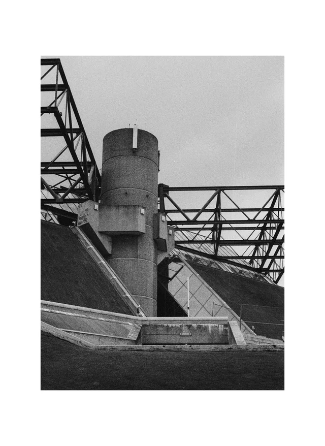 A cylindrical concrete tower surrounded by angular walls and exposed steel trusses