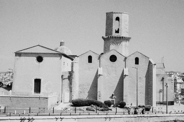 A pale stone church with a square bell tower and round windows