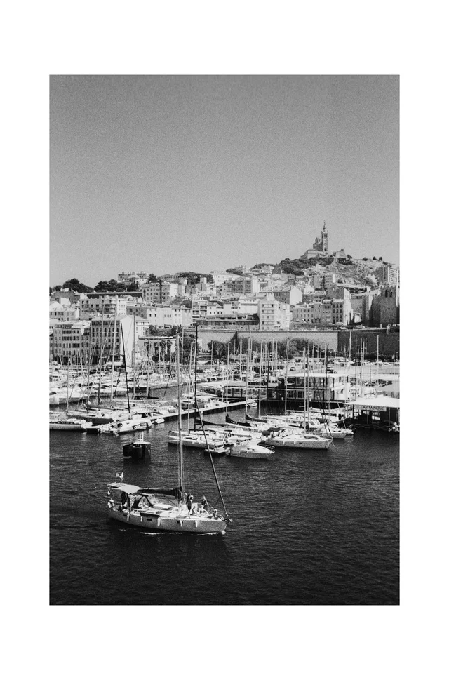 Sailboats in a marina below a densely built hillside