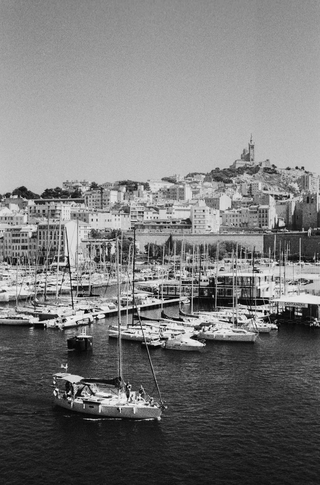 Sailboats in a marina below a densely built hillside