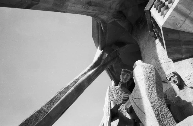 Angular stone figures beneath projecting beams on a sculpted building facade
