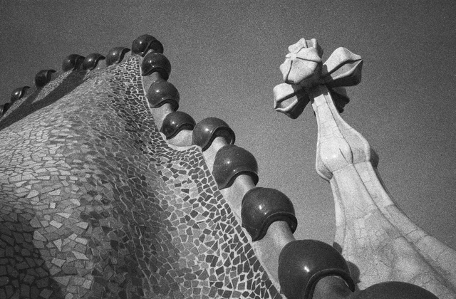 A curved mosaic-covered rooftop with rounded ridge tiles and a sculptural cross