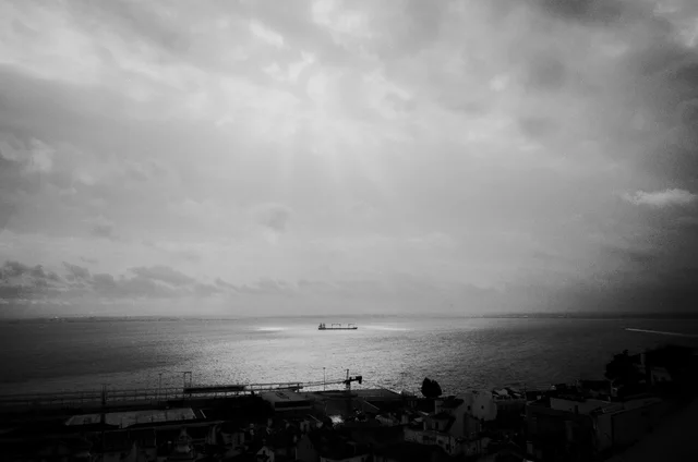 Sunbeams breaking through clouds over the sea and a distant ship