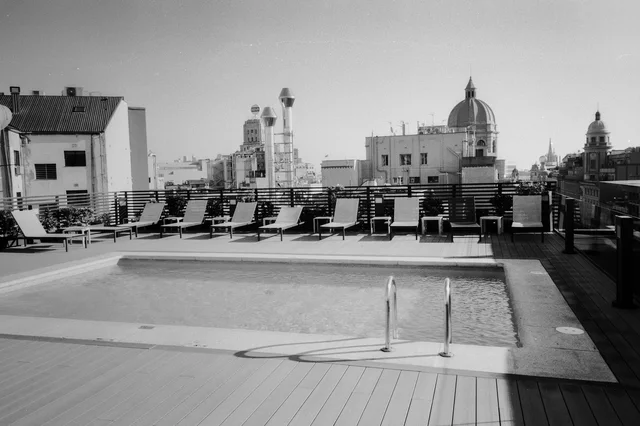 A rooftop swimming pool surrounded by deck chairs with domed buildings beyond