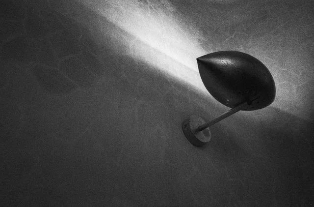 A wall-mounted lamp casting a bright fan of light across a textured wall