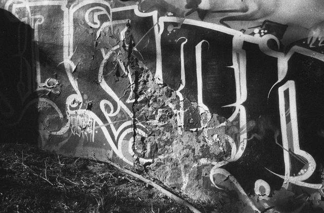 Large graffiti letters across a rough and crumbling wall