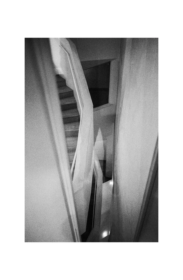 A narrow stairwell with curving pale walls and railings