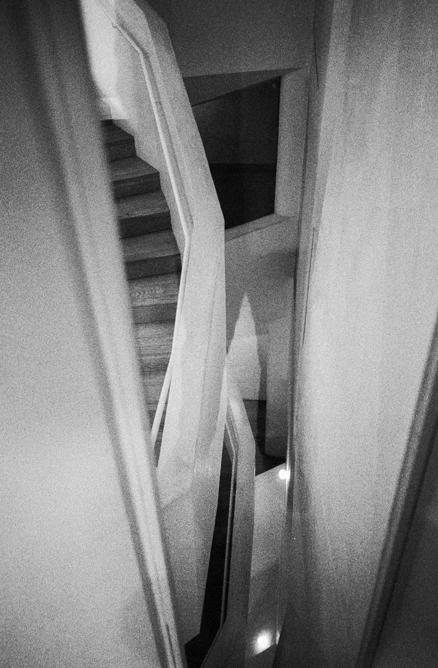 A narrow stairwell with curving pale walls and railings