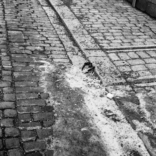 A narrow gutter crossing a cobbled street with patches of snow