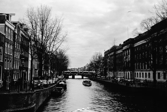 A canal lined with brick houses, bare trees and moored boats