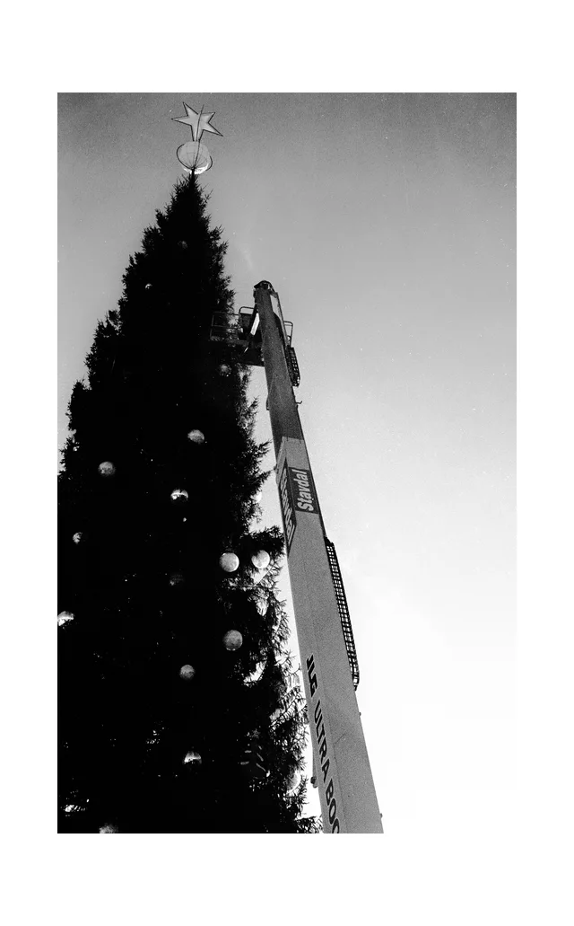 A decorated evergreen tree topped with a star beside an elevated work platform