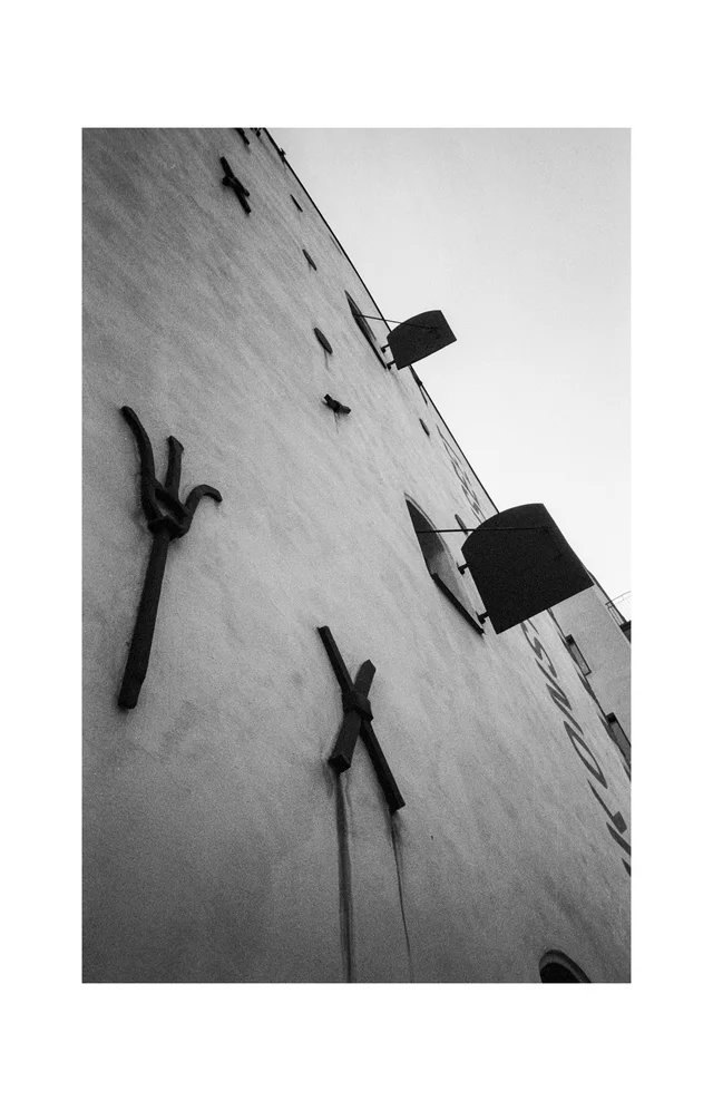 Metal brackets and small windows on a tall building wall viewed from below