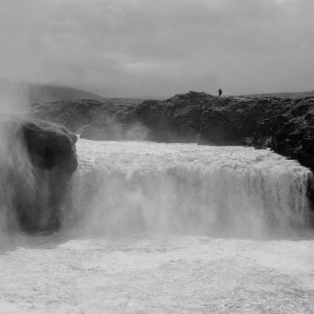 A broad waterfall surging between dark rocky banks