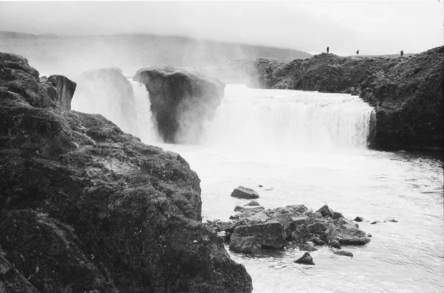 A waterfall and foaming river framed by dark rocks