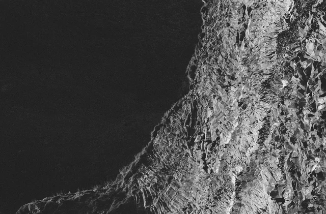 A steep textured rock face rising against a dark sky