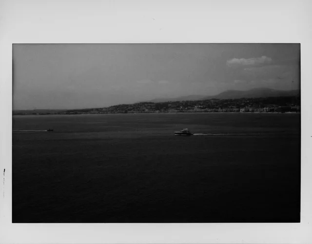 A small boat on dark water with a distant hilly shoreline