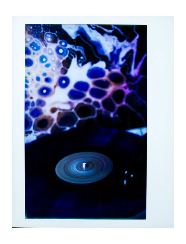 A record turntable beneath a glowing blue and purple abstract display