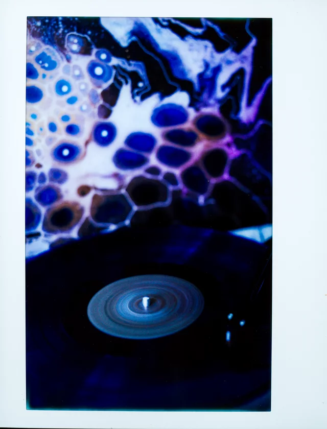 A record turntable beneath a glowing blue and purple abstract display