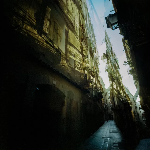 A narrow alley with shadowed doorways and sunlit upper walls
