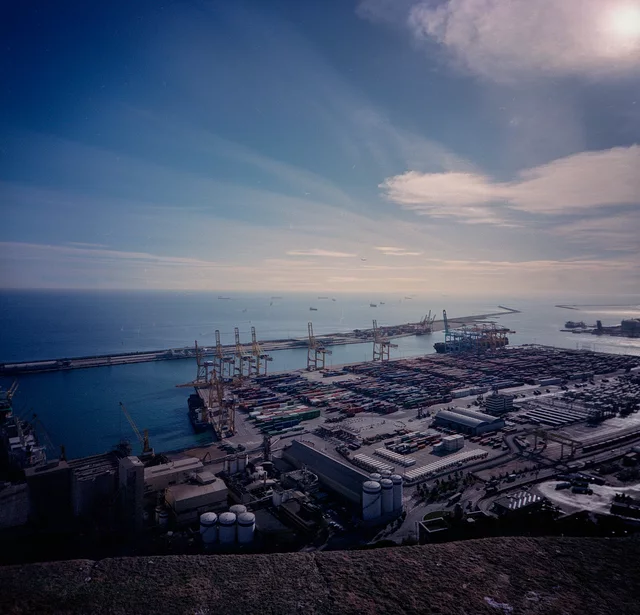 Harbour cranes and container yards beside calm blue water