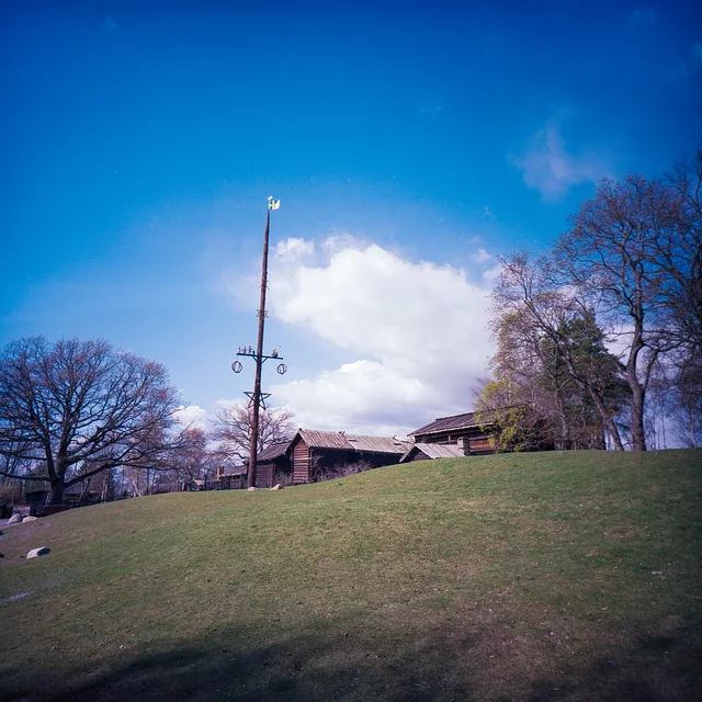 An open grassy slope and tall flagpole beneath a bright blue sky