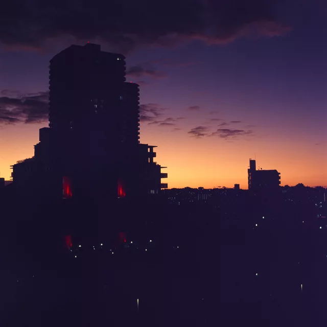Tall buildings silhouetted against an orange and purple sunset
