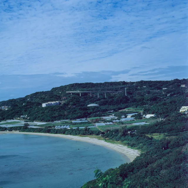 A curved sandy bay beneath green coastal hills
