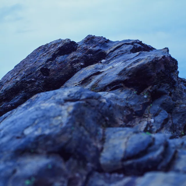 A close view of rough coastal rock beneath a pale blue sky