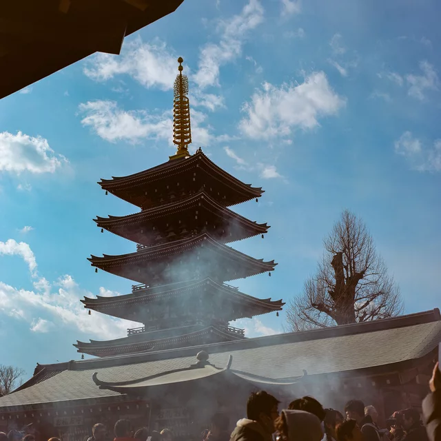 A tiered pagoda above temple roofs, with smoke drifting through the foreground