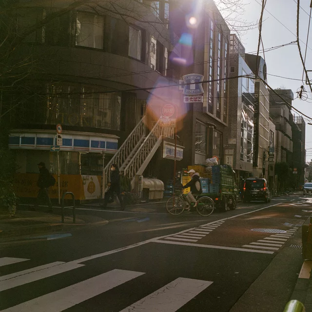 Sunlight flaring over a city street with a pedestrian crossing and exterior staircases