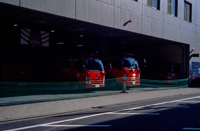 Two red fire engines parked inside a shadowed garage