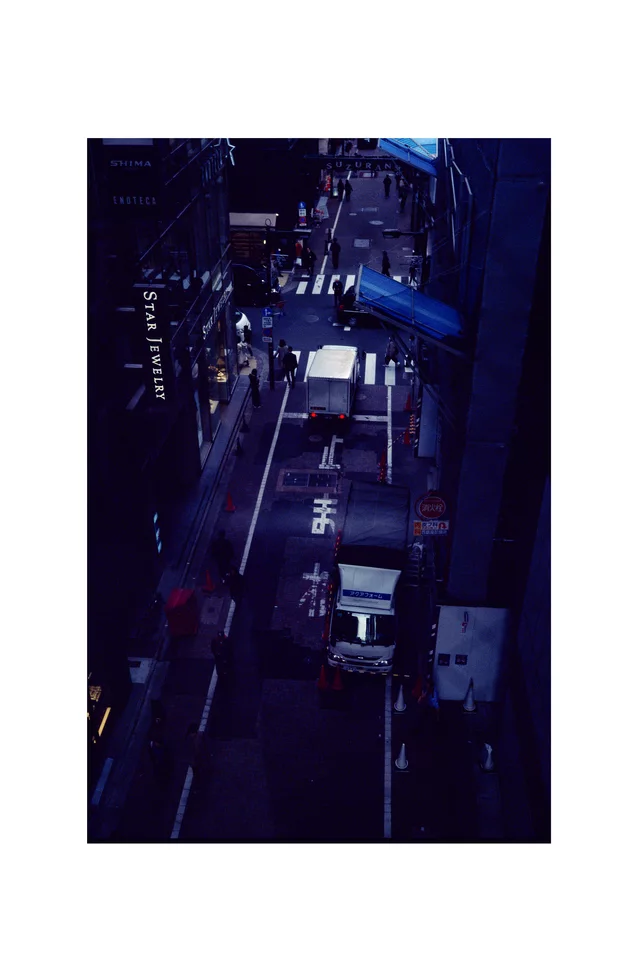 A narrow city street seen from above between tall buildings