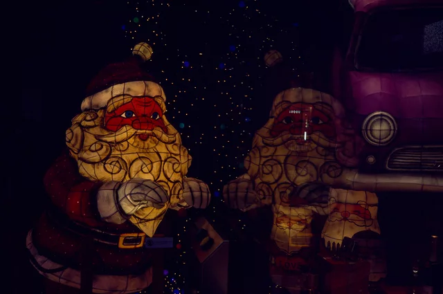 Two glowing Santa Claus decorations against a dark background